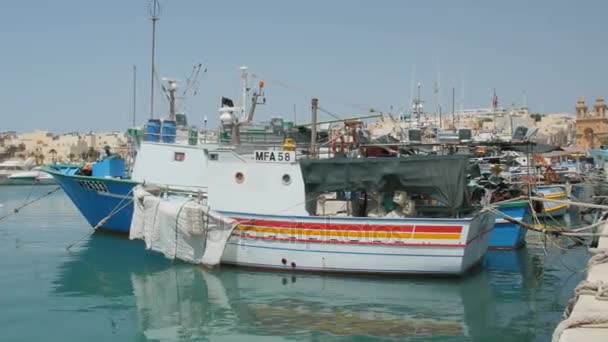 Marsaxlokk, Malta - 6 juli 2016: Vackra fiske byn arkitektur med färgade båtar ankar i en vik — Stockvideo