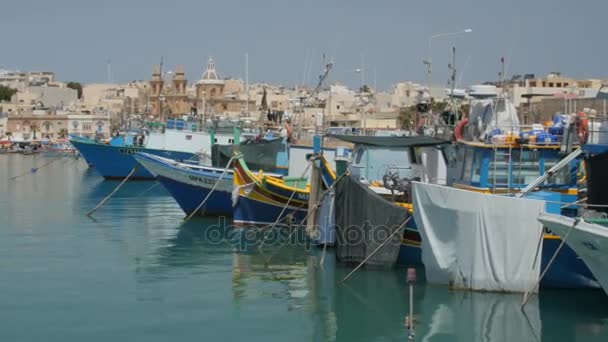 Marsaxlokk, Málta - július 6., 2016: Szép halászati falu építészet-val színes csónakok a horgony az öbölben — Stock videók