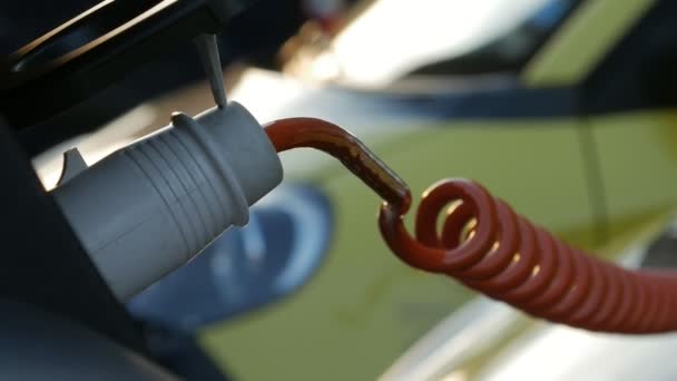 Primer plano de un vehículo eléctrico amarillo enchufado al puerto de carga . — Vídeos de Stock