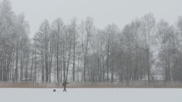 冬季捕鱼。孤独的渔夫坐在冰上钓鱼. — 图库视频影像