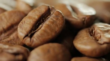Kahve çekirdekleri yakın çekim. Kamera önünde plaka kahve çekirdekleri ile döner.