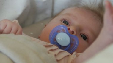 Üç aylık bebek battaniye var bir emzik ile yalan. Bebek yüz yakın çekim.