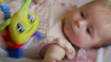 Küçük gülümseyen bir oyuncak bebekle. Mutlu bebek oyuncak asılı ile oynamak.