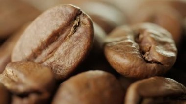 Kahve çekirdekleri yakın çekim. Kamera önünde plaka kahve çekirdekleri ile döner.
