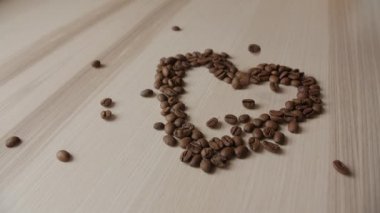 Kahve çekirdekleri ahşap bir masa üzerinde. Düşen kahve çekirdekleri arka plan. Kahve çekirdekleri kalbinde.