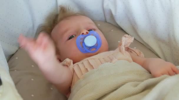 Bebé de tres meses acostado en una manta con un chupete. La cara de bebé de cerca . — Vídeo de stock