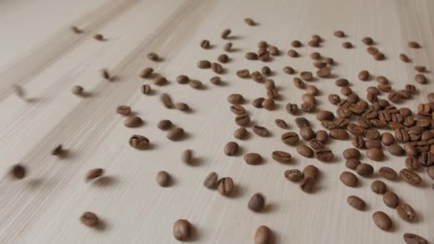 Granos de café tostados derramados en tablón de madera — Vídeo de stock