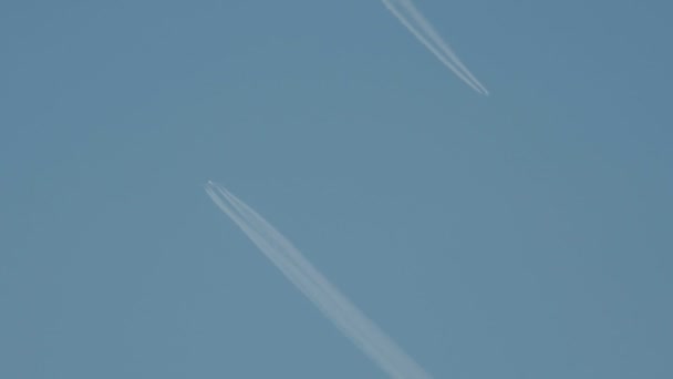 青い空に白のストライプを作る飛行の飛行機は、飛行機雲との呼ばれる、歩道または蒸気トレイルを凝縮. — ストック動画