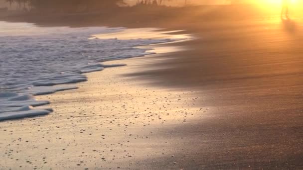 Bílé moře přijíždějící pěnové vlny pokrývá písčité pobřeží při krásném západu slunce. Zavřít, zpomalit.. — Stock video