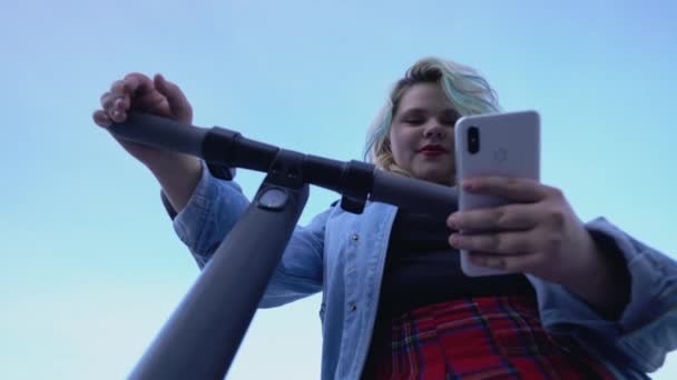 Jeune femme active debout près de scooter électrique dans la rue de la ville, en utilisant un gadget — Video