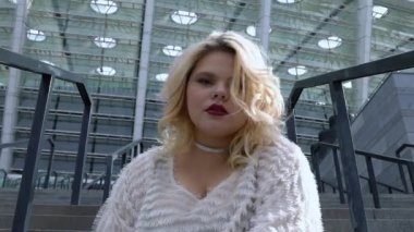 Cilveli tombul kız merdivenlerde oturuyor ve gülümsüyor, romantik bir ruh hali, aşık bir kadın.