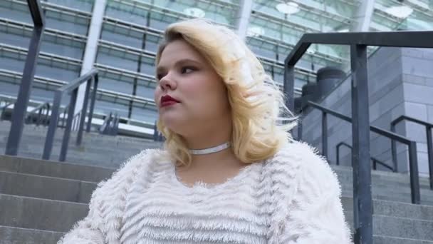 Stijlvolle jonge vrouw luisteren muziek in koptelefoon, buiten zitten, levensstijl — Stockvideo