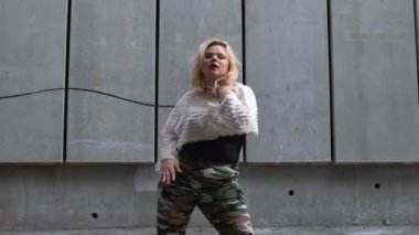 Oldukça tombul bir sokak dansçısı açık havada müzik yapıyor, aktif bir hobiden hoşlanıyor.