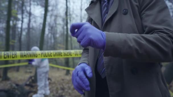 Investigador usando guantes, equipo forense trabajando detrás de la cinta de la escena del crimen — Vídeo de stock