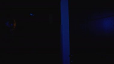 Polis elinde silahla karanlık koridorda yürüyor, tehlikeli suçluları tutuklamaya hazır.