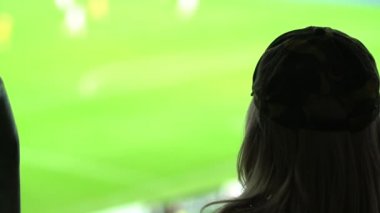 Stadyumda futbol maçı izleyen bir kadın gol bekliyor.