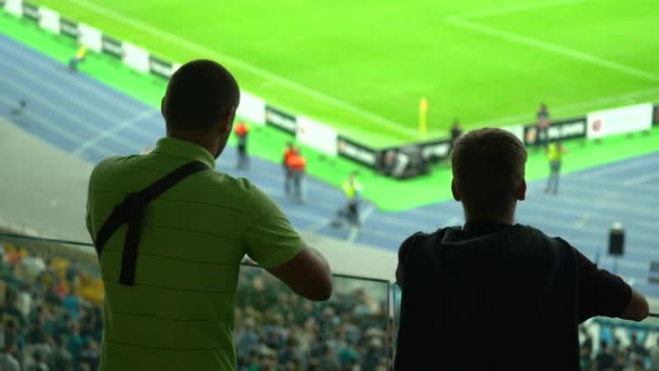 Två manliga supportrar tittar på fotbollsmatch på stadion, fans — Stockvideo