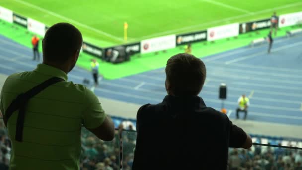 Twee sportfans kijken naar de wedstrijd in het stadion, vrienden brengen tijd samen door — Stockvideo