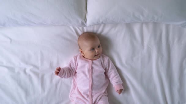 Bebê recém-nascido saudável deitado na cama, ativamente movendo as mãos e pernas, infância — Vídeo de Stock
