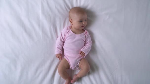 小さな指を噛む素敵な赤ちゃんの女の子、不思議なことに周りを見て、幸せな幼児 — ストック動画