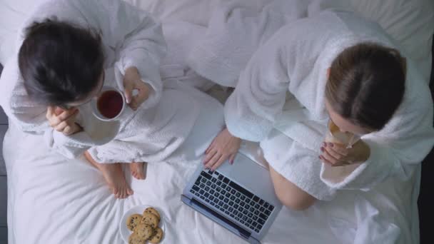 Vista superior de las mujeres jóvenes hablando por teléfono y utilizando el ordenador portátil en la cama, freelance — Vídeos de Stock