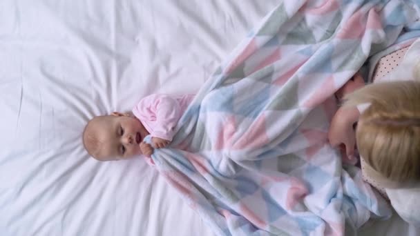 Happy mother playing with cute baby in bed after morning wakeup, parenthood — Stock Video