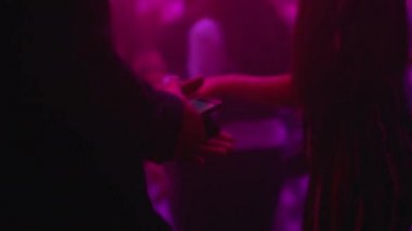 Genç adam partide akıllı telefon uygulaması kullanıyor, gece kulübünde müzik eşliğinde dans ediyor.