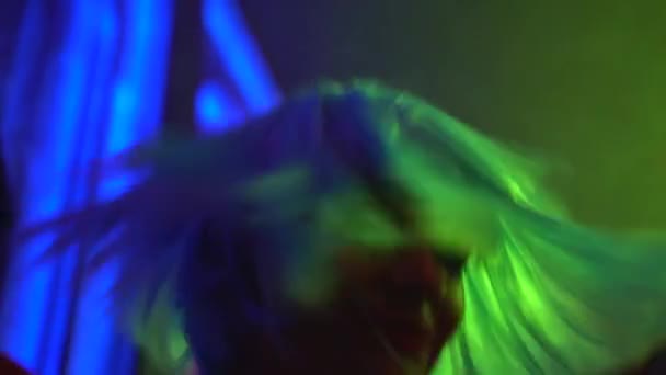 Gece kulübünde dans eden renkli saçlı mutlu kız, parti atmosferinin tadını çıkarıyor. — Stok video