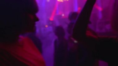 Gece kulübü partisinde kalabalık içinde dans eden neşeli genç kadınlar, eğlenen arkadaşlar.