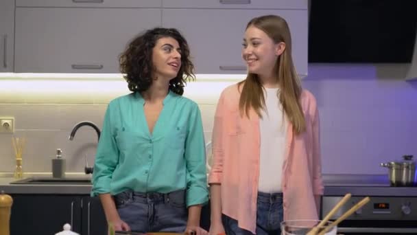 Les jeunes femmes gaies se sourient, debout dans la cuisine, couple lesbien — Video