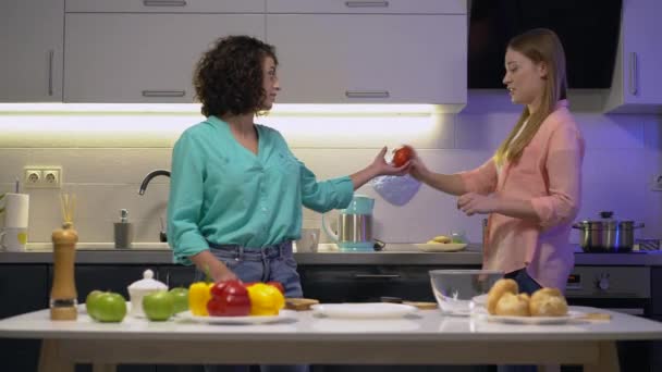 Vacker biracial kvinna som tar grönsaker ur vännens hand, matlagning tillsammans — Stockvideo