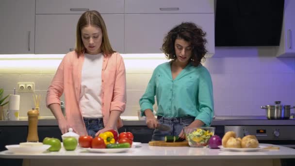 Junge hübsche Frauen reden in der Küche, bereiten Gemüsemahlzeit zu, kommunizieren — Stockvideo