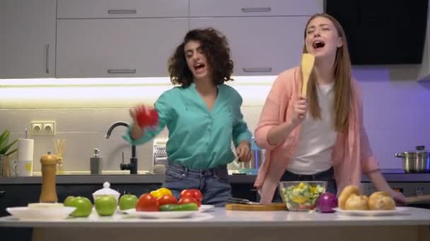 Hermanas positivas bailando, cantando en la cocina, amigas despreocupadas divirtiéndose — Vídeo de stock