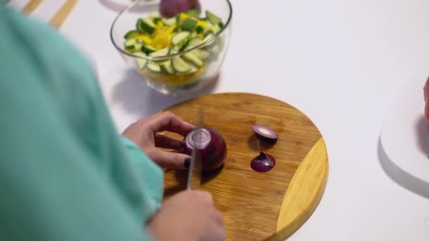 Жінка ріже червону цибулю ножем, готує свіжий салат, здорову їжу. крупним планом — стокове відео
