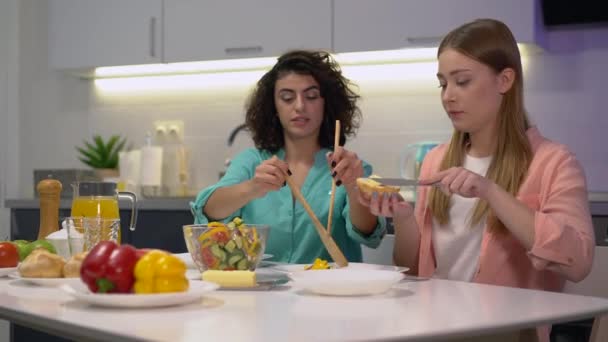 Beautiful woman serving salad to female friend, women having breakfast together — Stock Video