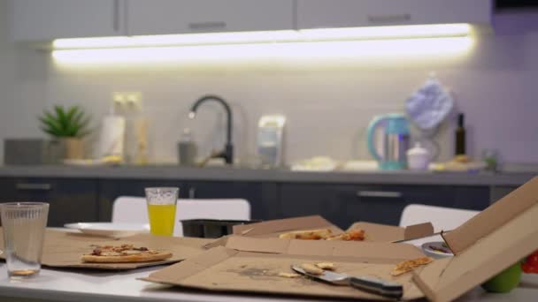 Pizza restante, boîtes en carton et verres sur la table, ménage sale, nettoyage — Video