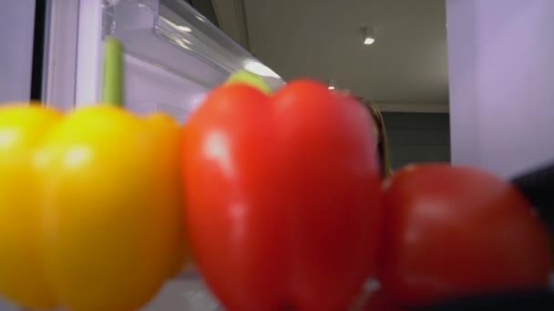 Joven hembra caucásica abriendo nevera y tomando pimientos, comiendo sano — Vídeos de Stock