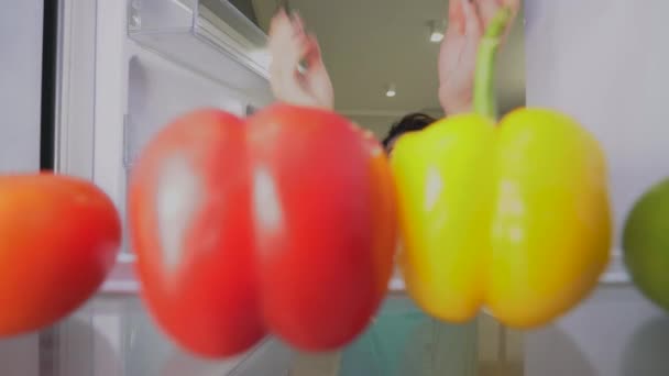 Joven hembra abriendo nevera y tomando contenedor de alimentos y verduras frescas — Vídeos de Stock