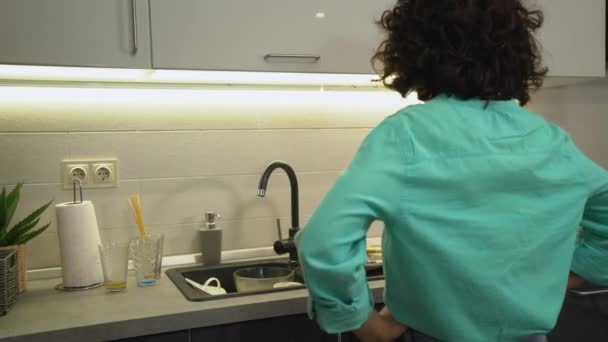Disappointed woman looking at lots of dirty plates in kitchen washbasin, maid — Stock Video