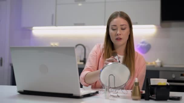 Female blogger applying cosmetics in front laptop camera, promoting goods online — Stock Video