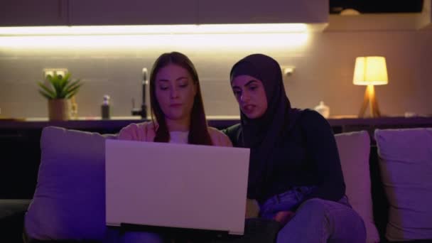 Busy female friends sitting on couch with laptop, searching information online — 图库视频影像