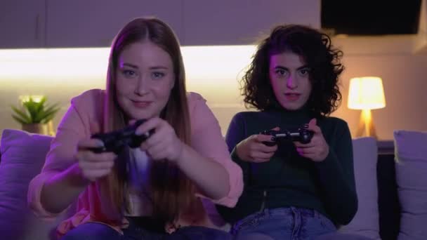 Возбужденные молодые женщины играют в видеоигры дома вместе, наслаждаясь вечерним отдыхом — стоковое видео
