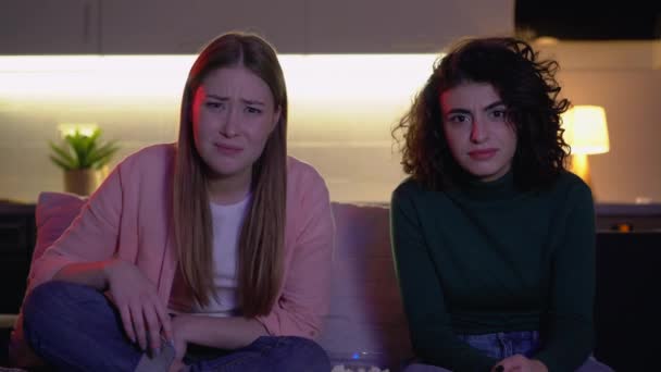 Dvě ženy sledují divnou show v televizi, vypadající zmateně a překvapeně zprávami — Stock video