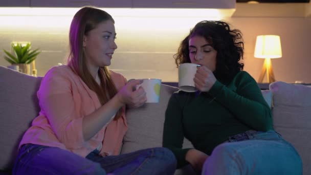 Meninas bebendo chá delicioso, desfrutando de conversa no sofá, amizade estreita — Vídeo de Stock