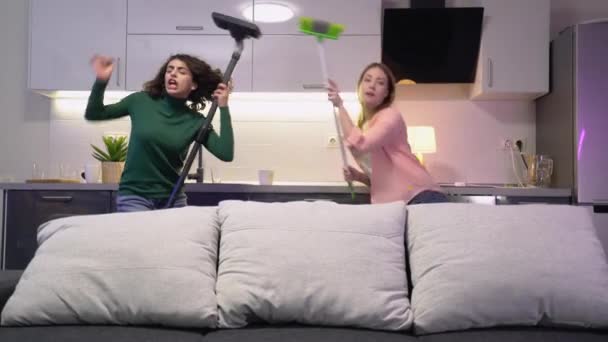 Twee vriendinnen schoonmaken appartement samen, dansen met gereedschap, plezier hebben — Stockvideo