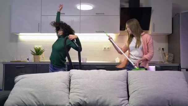 Dos chicas divertidas bailando mientras limpian casa, divirtiéndose, amistad, familia — Vídeos de Stock