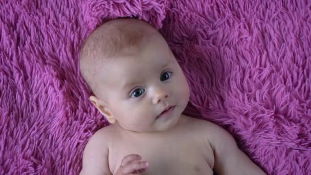 Söta nyfödda barn nyfiket tittar runt, ler och babblar i mysig säng — Stockvideo