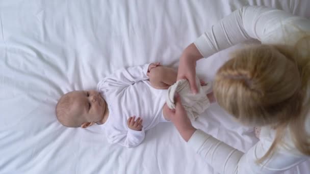Молодая мать одевает любимую малышку в органическую хлопковую одежду, комфорт — стоковое видео