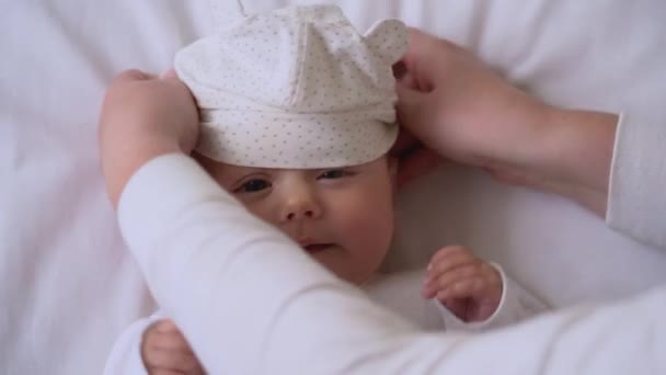 Anne, sevimli aktif bebeğe komik bir şapka takıyor. Alerjisi olmayan pamuk. — Stok video