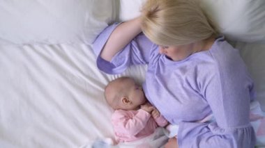 Bakımlı genç anne uykulu kız bebeği emziriyor, yeni doğan bebek beslenme programı...